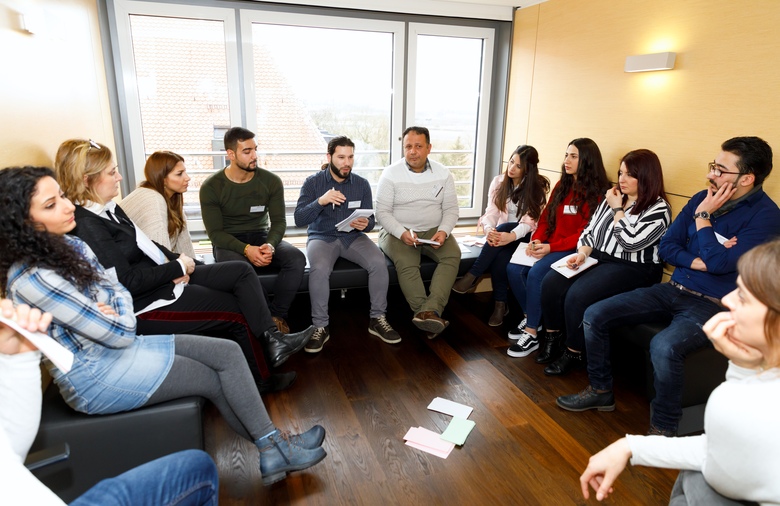 Zwölf syrische Praktikantinnen und Praktikanten sitzen in einem Stuhlkreis